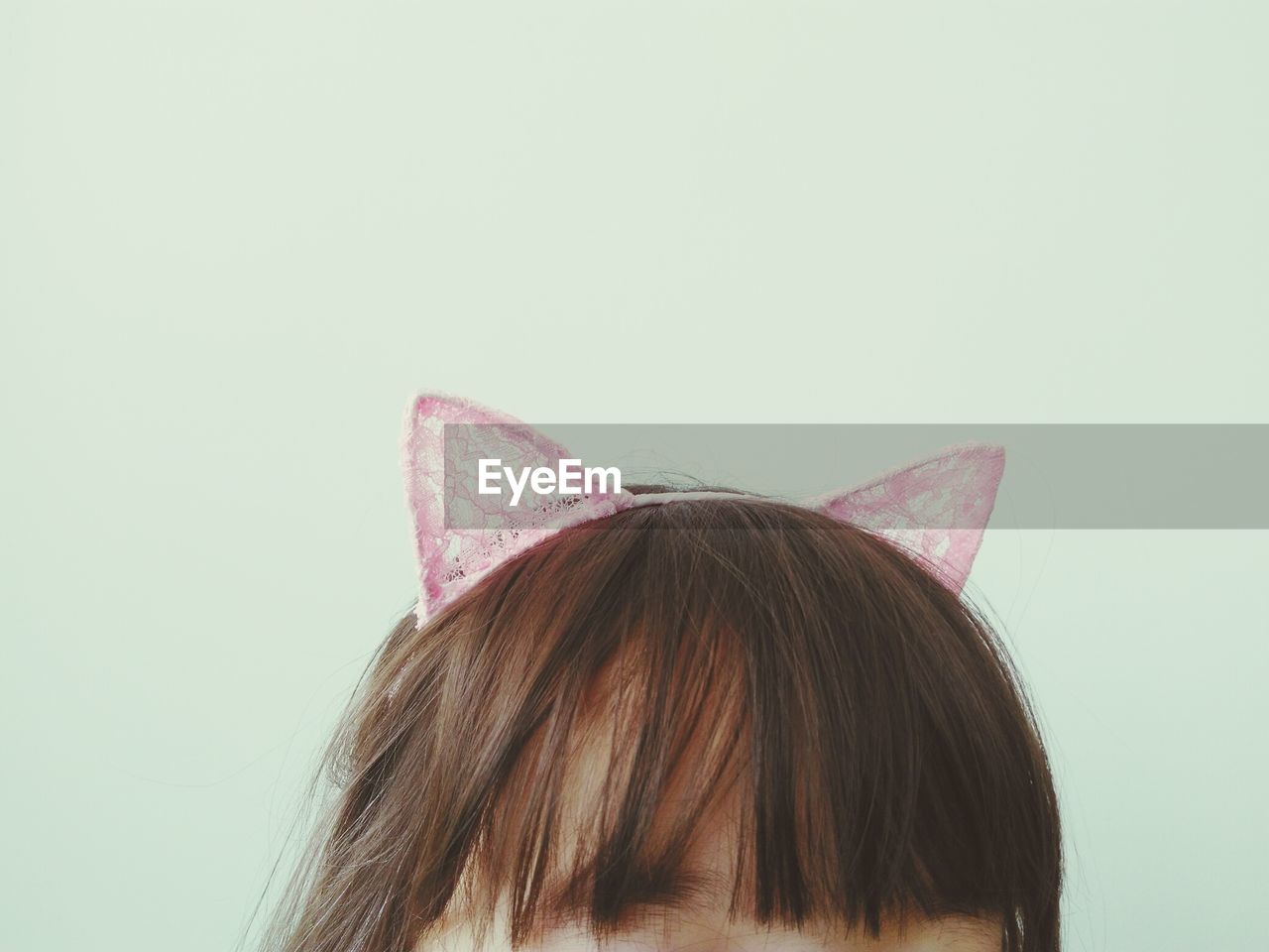 Close-up of girl wearing headband against white background