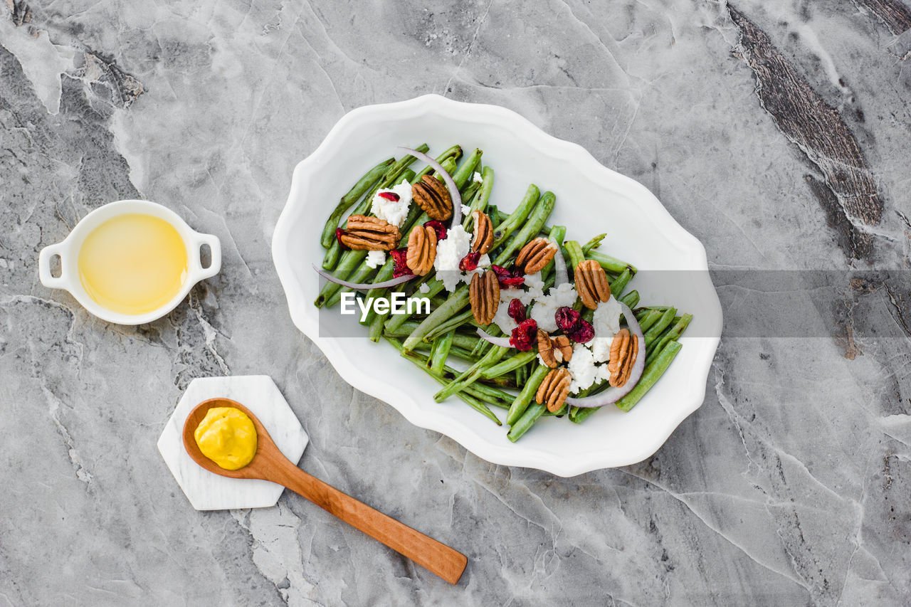 Salad with green beans and nuts on marble table