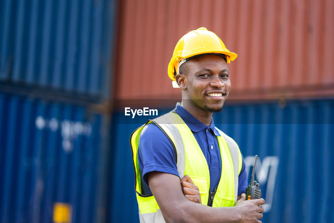 PORTRAIT OF SMILING MAN WORKING IN YELLOW