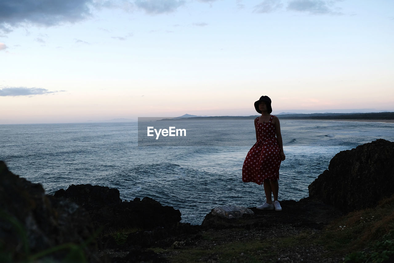 rear view of woman standing on beach against sky