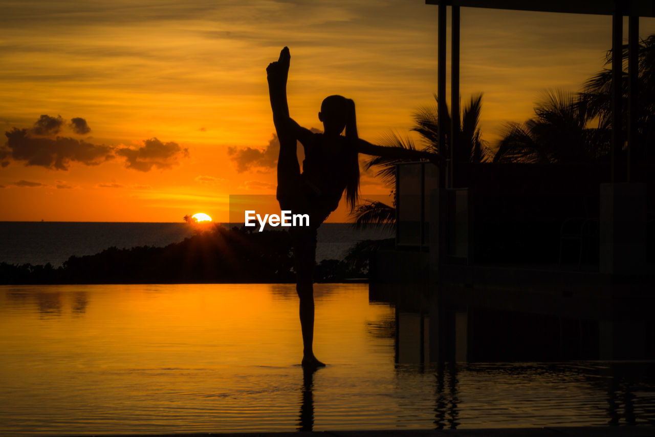 SILHOUETTE WOMAN WITH ARMS RAISED AT SUNSET