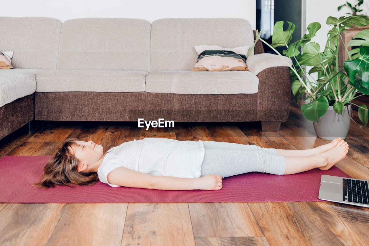 The girl lets out or meditates, lying on a yoga mat and closing her eyes. yoga for kids. assana