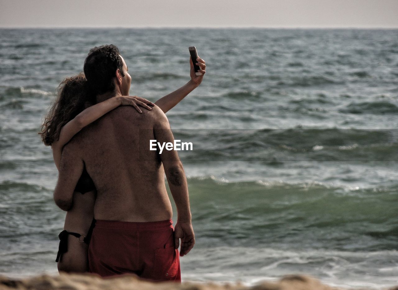 Couple taking selfie with smart phone at beach