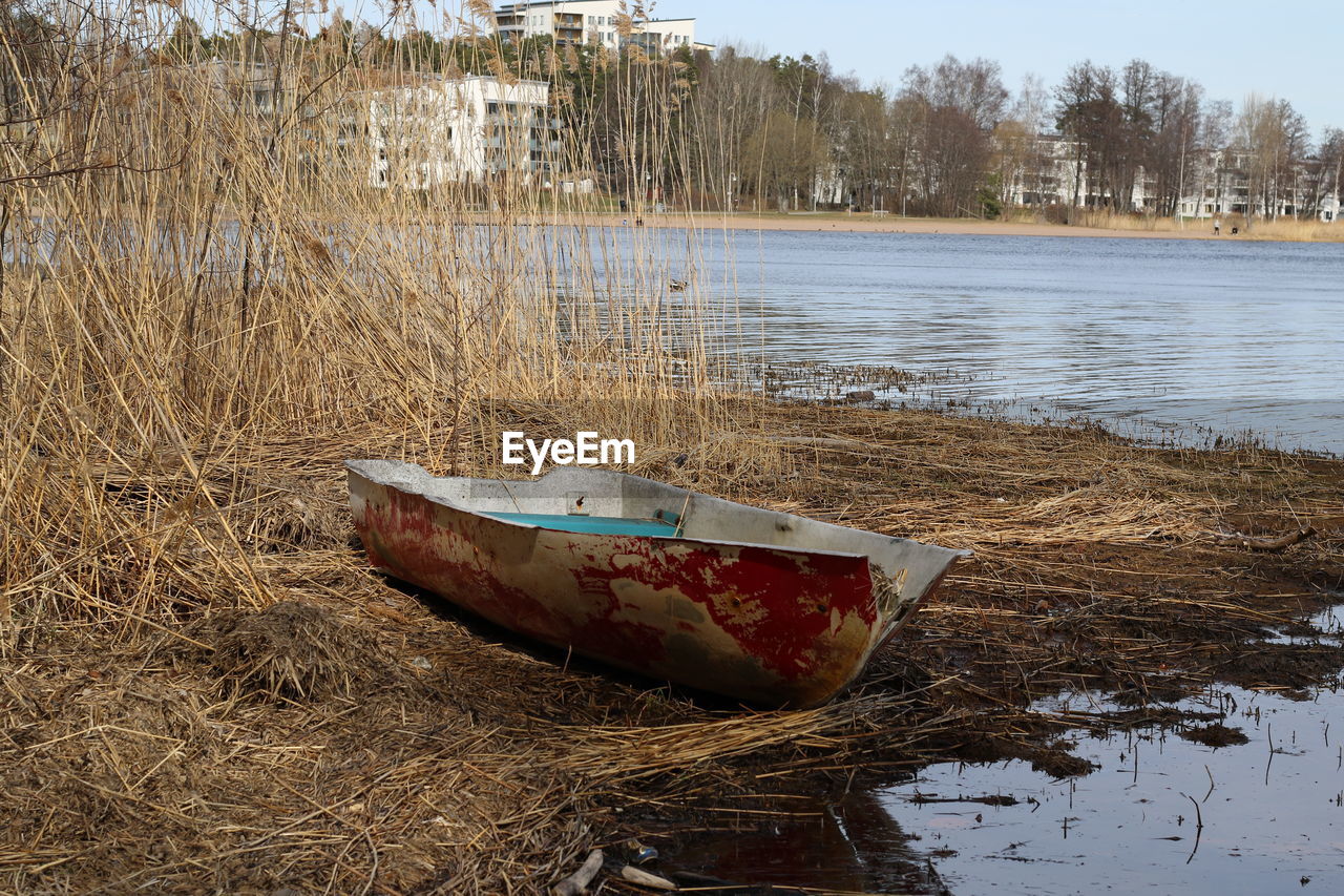 ABANDONED BOAT MOORED ON SHORE AT LAKE