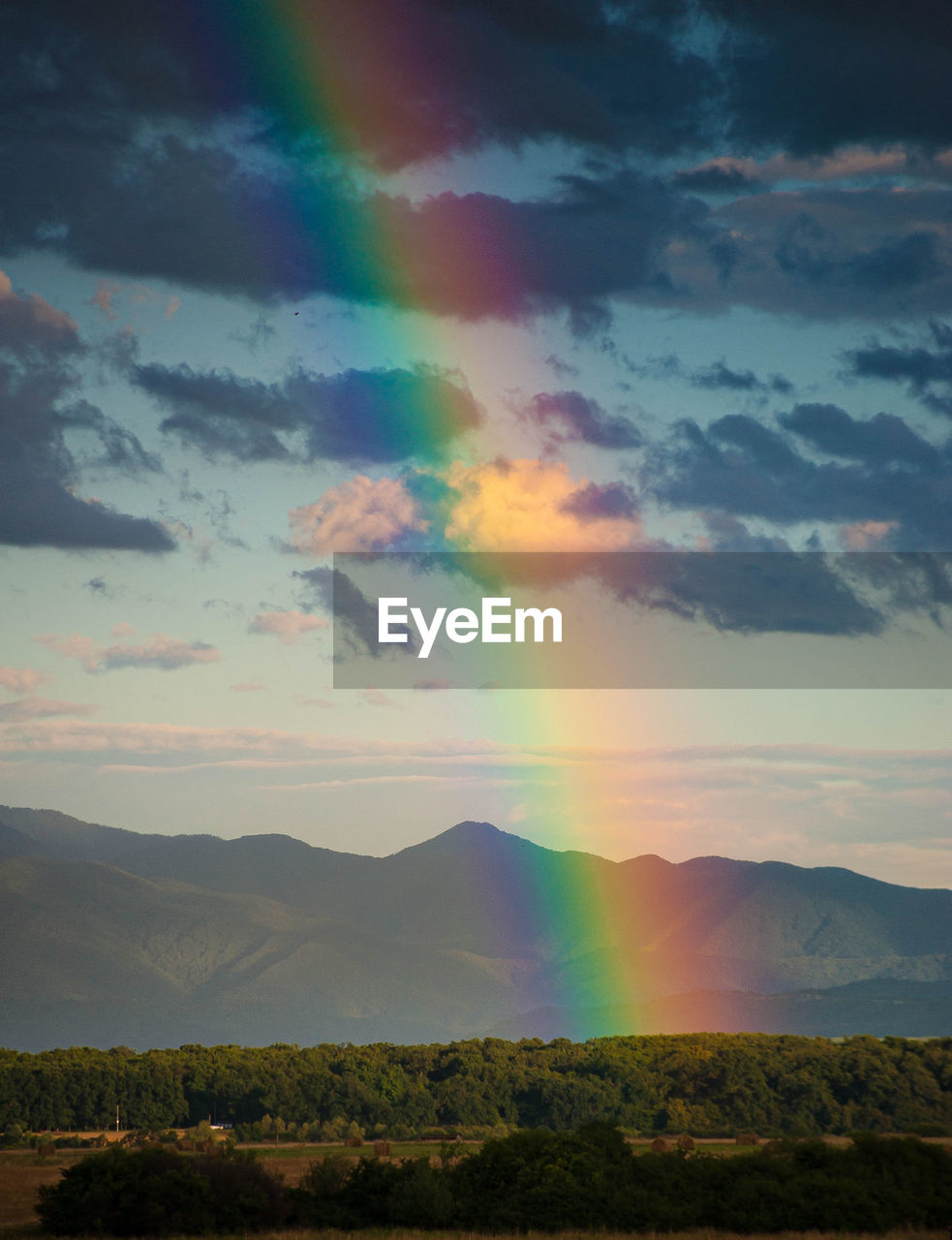 Scenic view of field against sky during sunset with rainbow