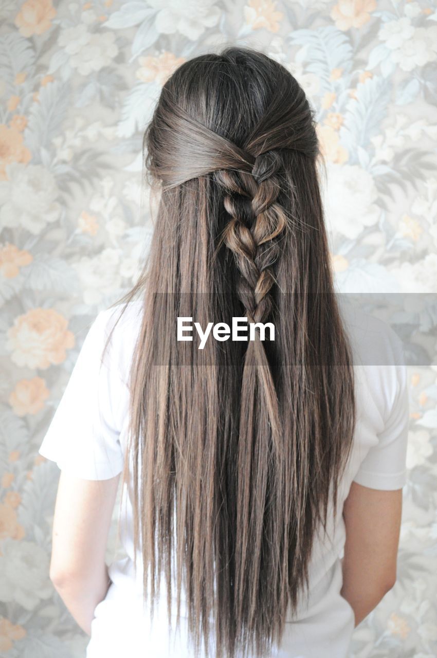 Rear view of woman with braided hair against wall