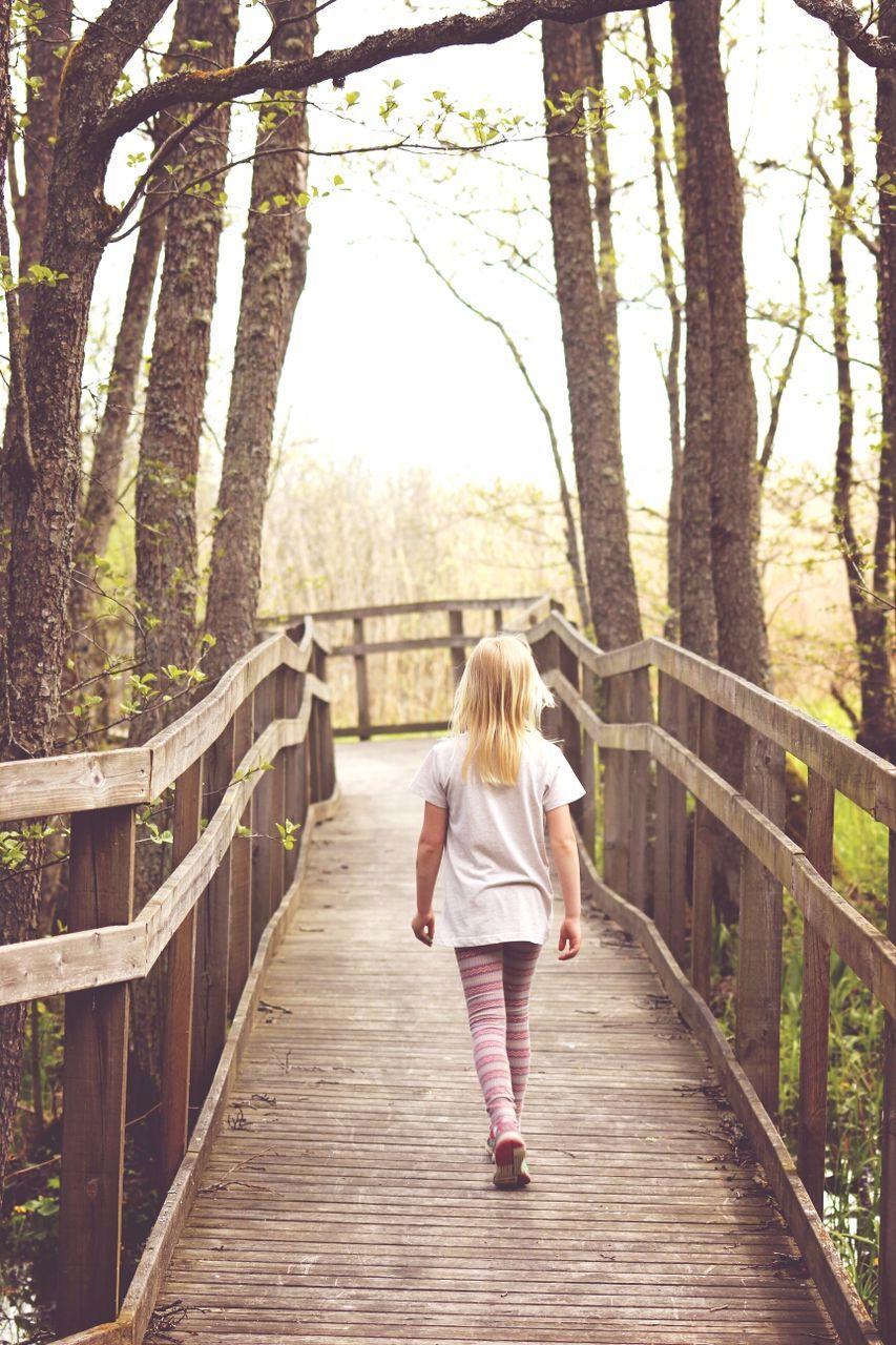 Girl walking away along wooden footbridge