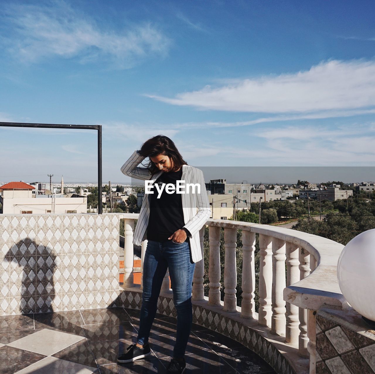 WOMAN STANDING BY RAILING AGAINST SKY