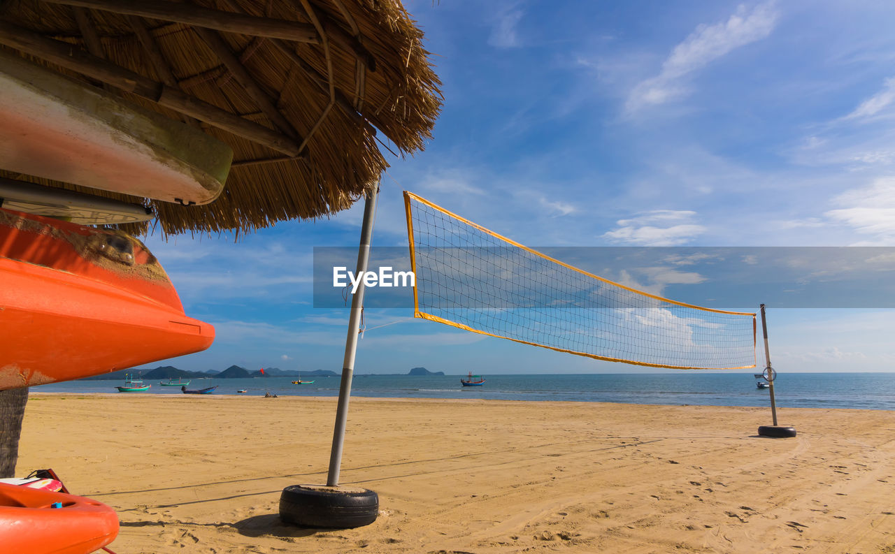 Volleyball net on beach by thatched roof