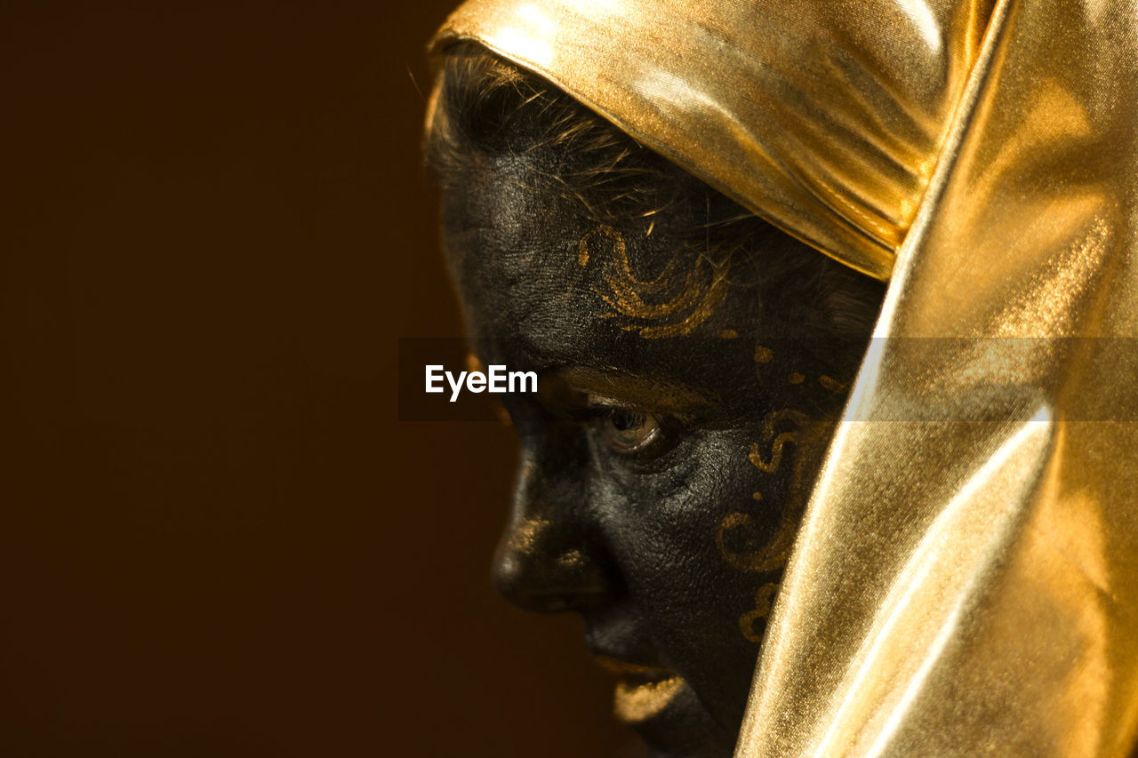 Portrait of a woman with black and gold make up, close up