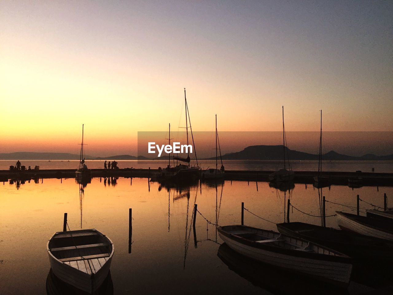 Boats moored in sea at sunset