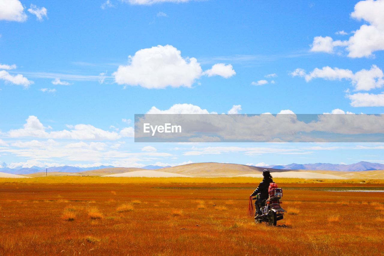 Man on motorcycle looking at hilly landscape