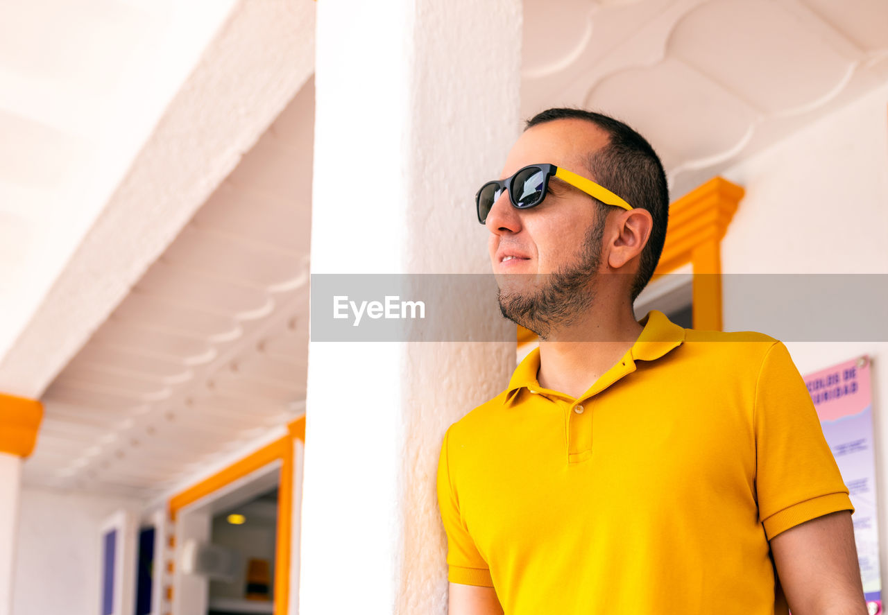 YOUNG MAN WEARING SUNGLASSES ON WALL