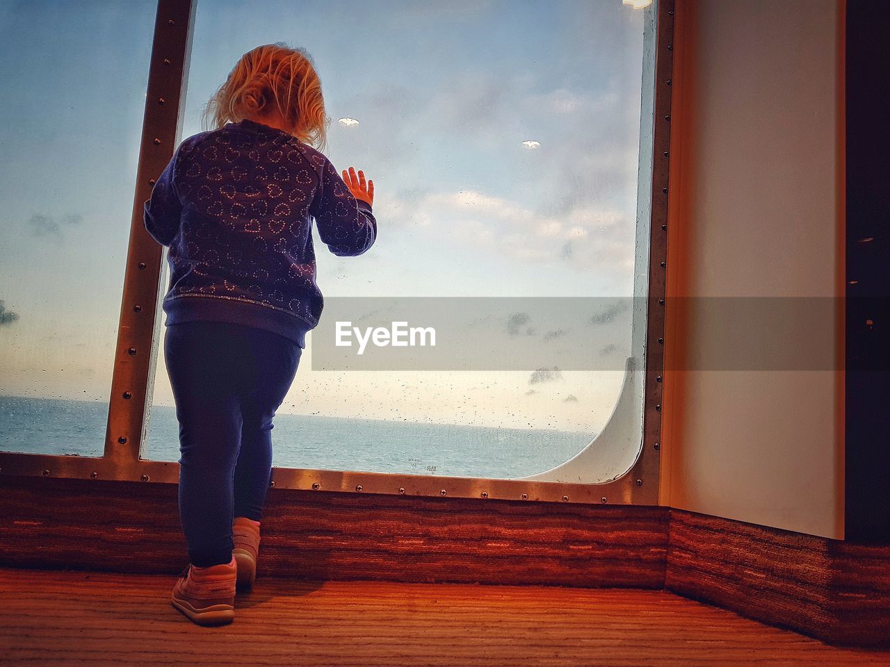 Rear view of girl standing in boat against sea