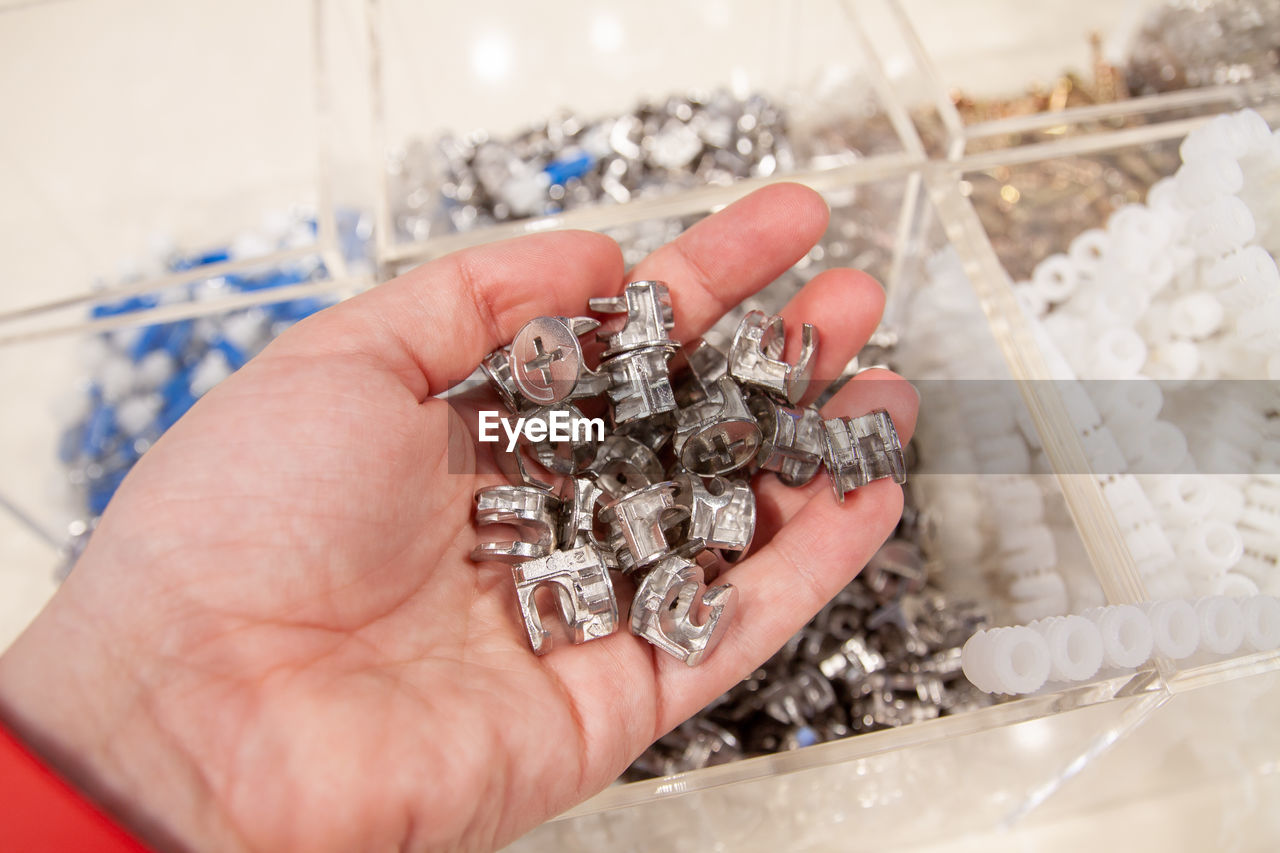 Human hand holding a pile of stainless steel construction fasteners