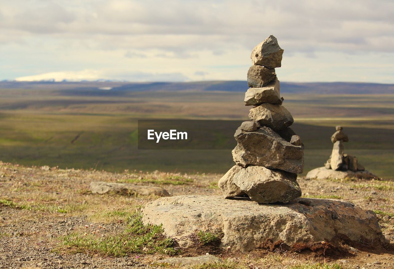 Stack of stones on landscape against sky