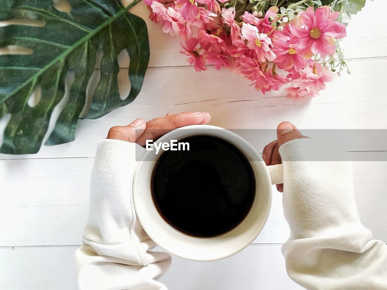 HIGH ANGLE VIEW OF COFFEE CUP ON TABLE BY WALL