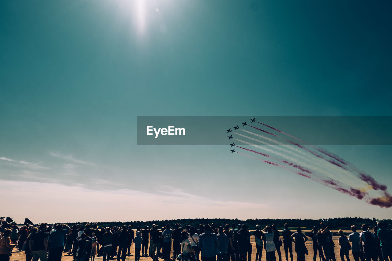 Crowd watching airshow against blue sky