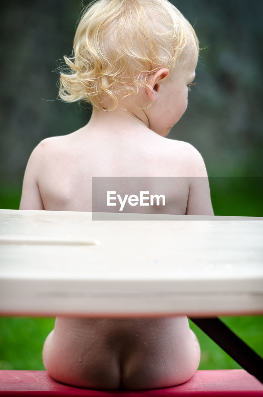 Close-up of naked boy sitting on bench