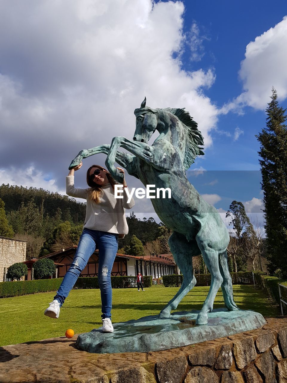Low angle view of woman standing by horse statue in park