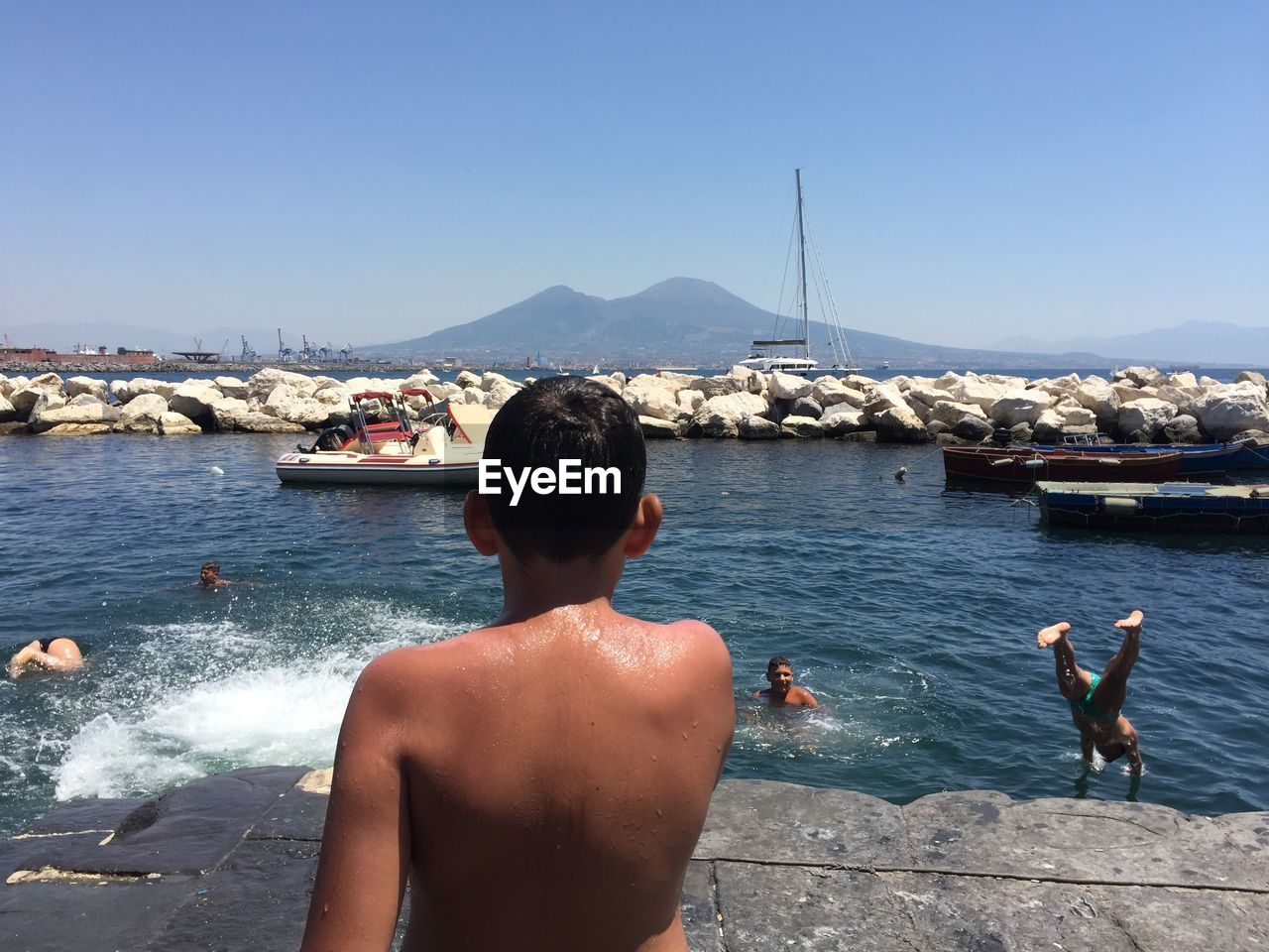 REAR VIEW OF MEN LOOKING AT SEA AGAINST SKY