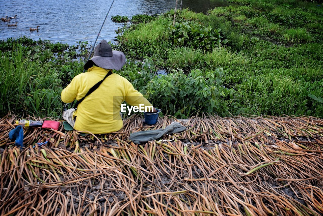 REAR VIEW OF MAN WORKING ON GRASS