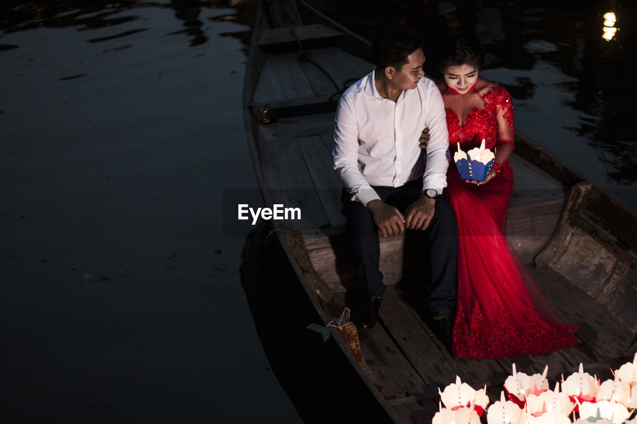 HIGH ANGLE VIEW OF MAN AND WOMAN HOLDING WHILE SITTING AT SHORE