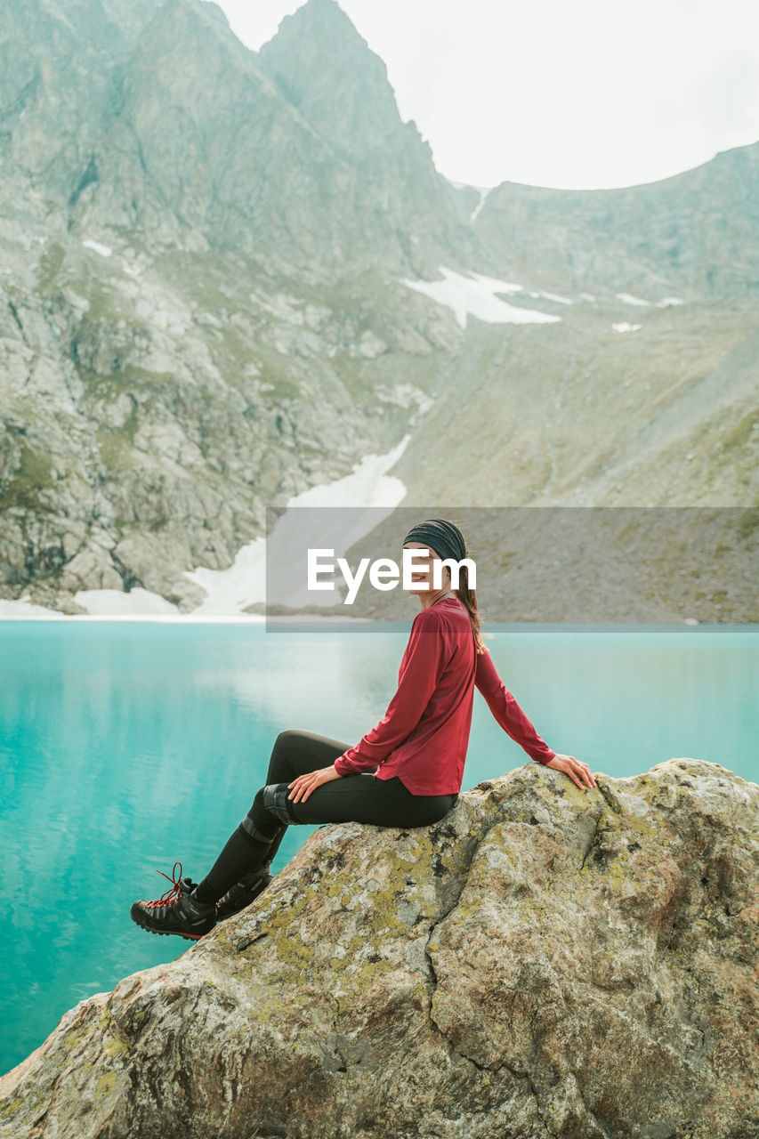 Woman sitting on rock by mountains