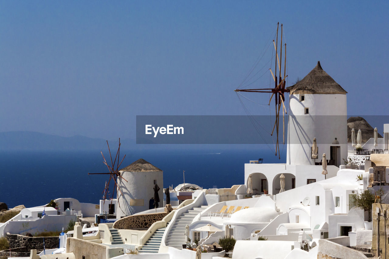 Traditional windmill by sea against sky