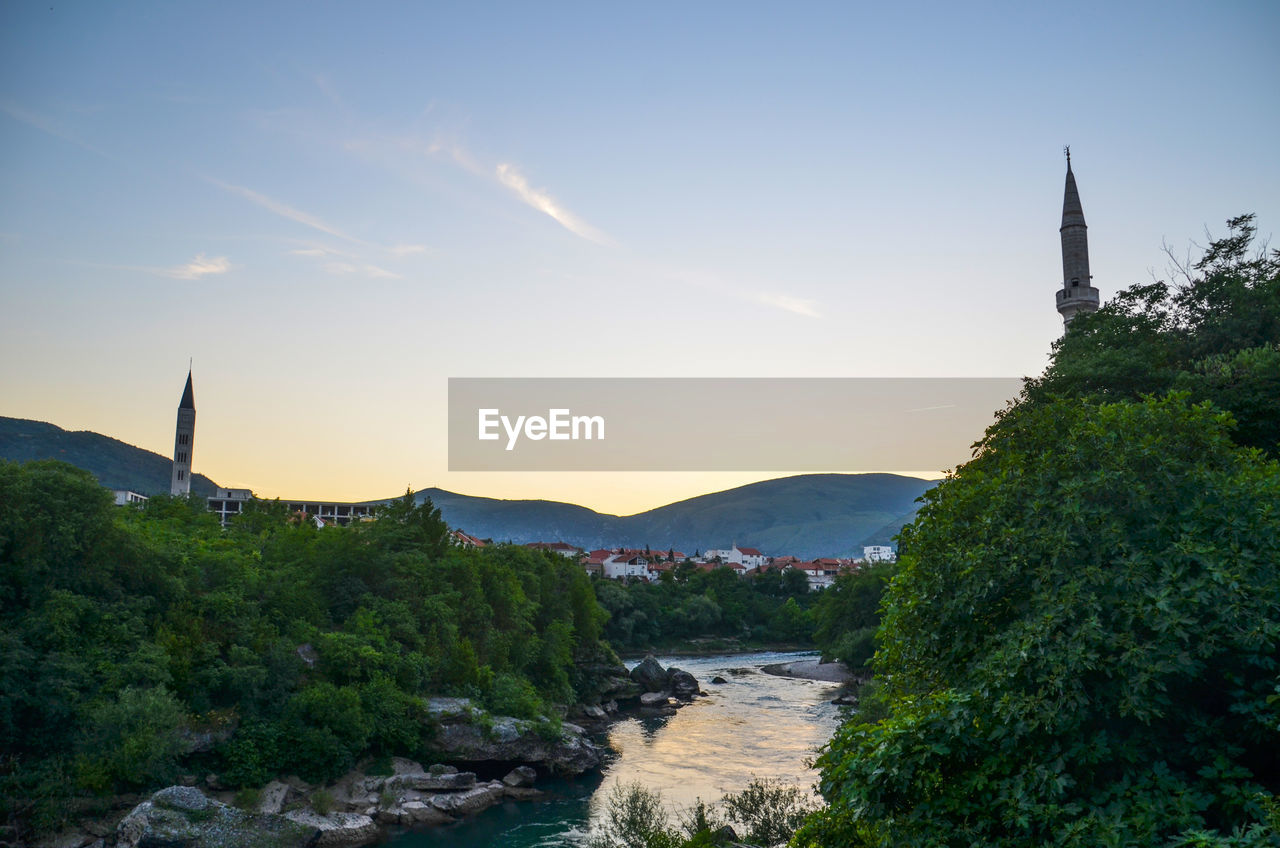 Scenic view of river amidst buildings against sky in mostar