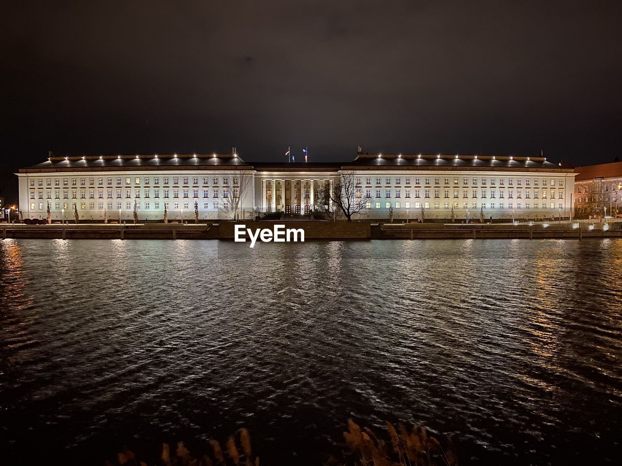 VIEW OF ILLUMINATED BUILDINGS AT WATERFRONT