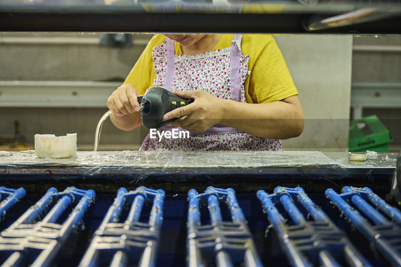 Detail of worker applying glue to the shoes sole in a production line of chinese shoes factory