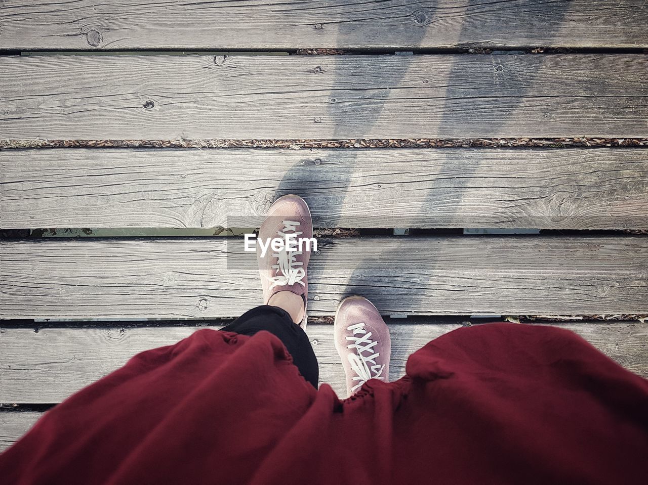 LOW SECTION OF WOMAN STANDING ON WOODEN PLANK