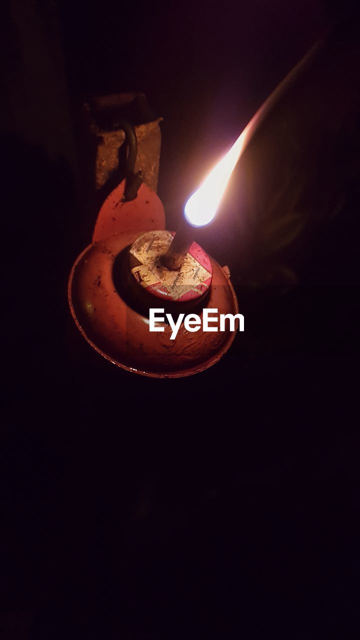 CLOSE-UP OF LIT CANDLE IN DARK