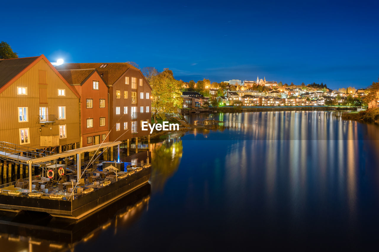 Illuminated buildings by nidelva river at night  in trondheim, norway