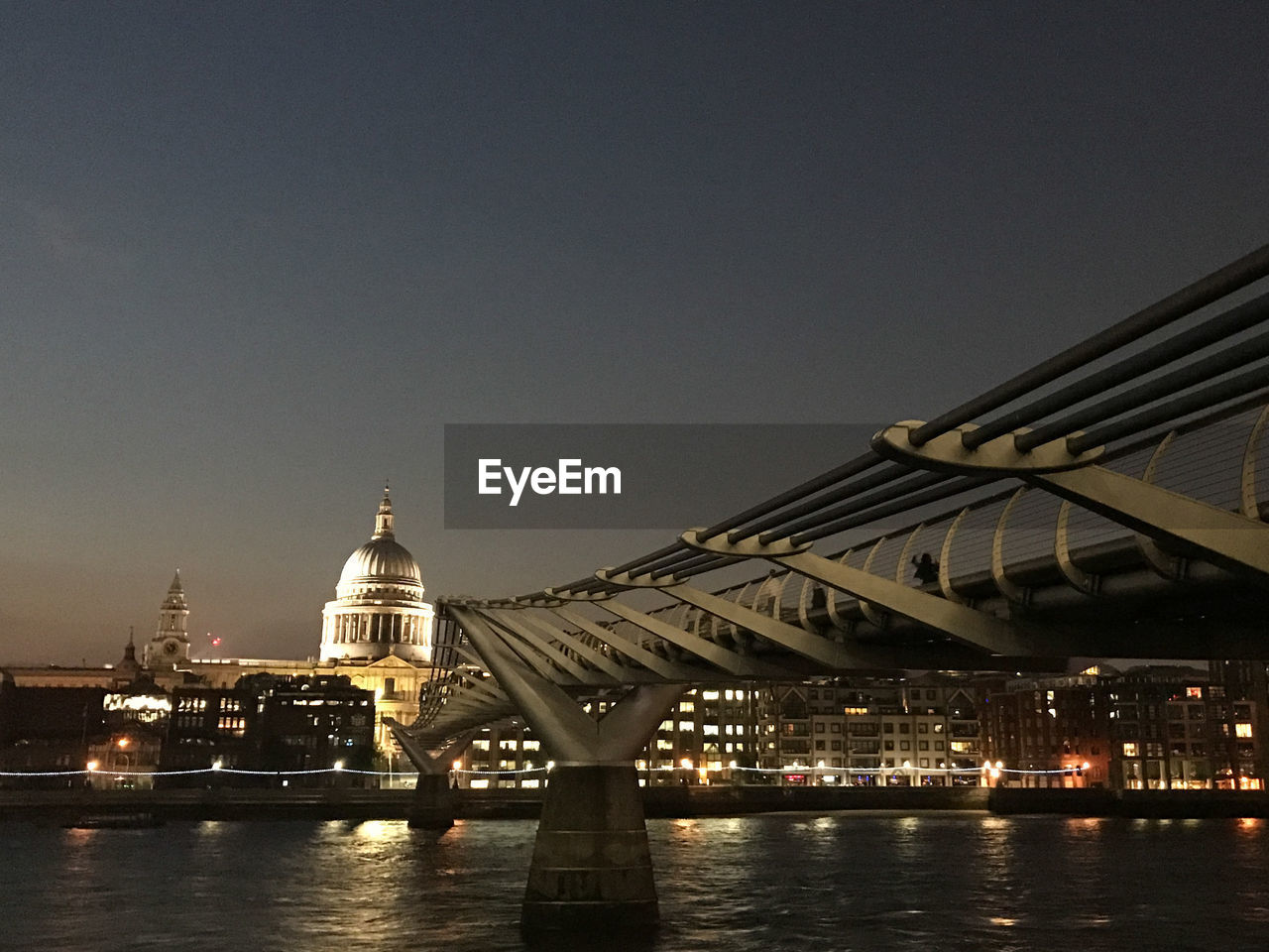 ILLUMINATED BRIDGE OVER RIVER AGAINST CLEAR SKY