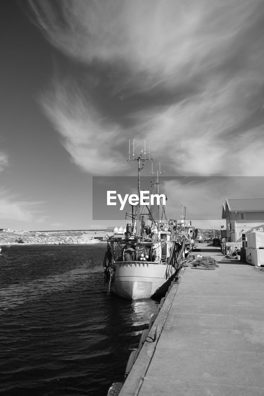 Boat moored at harbor against sky