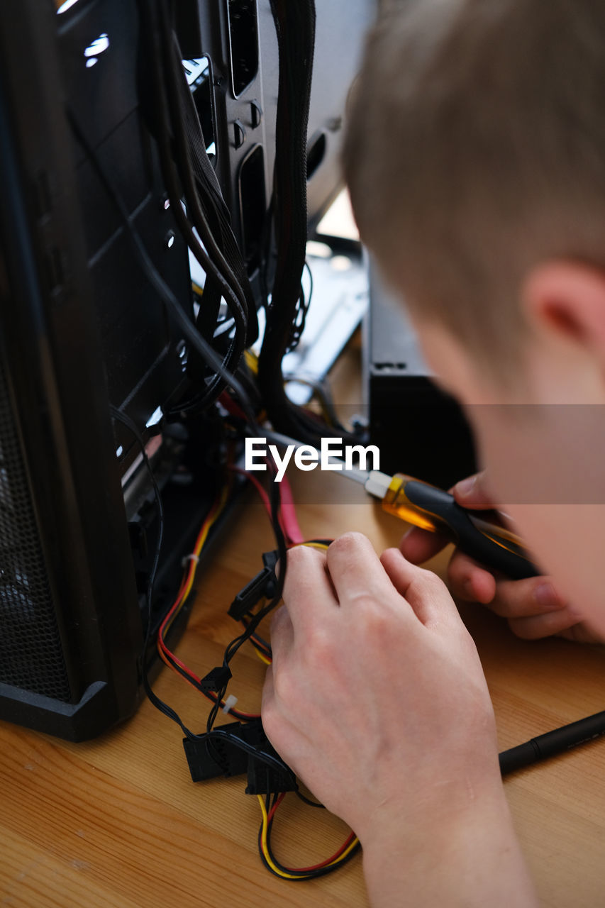 A man repairs a cable in a system unit and connects electrical wires