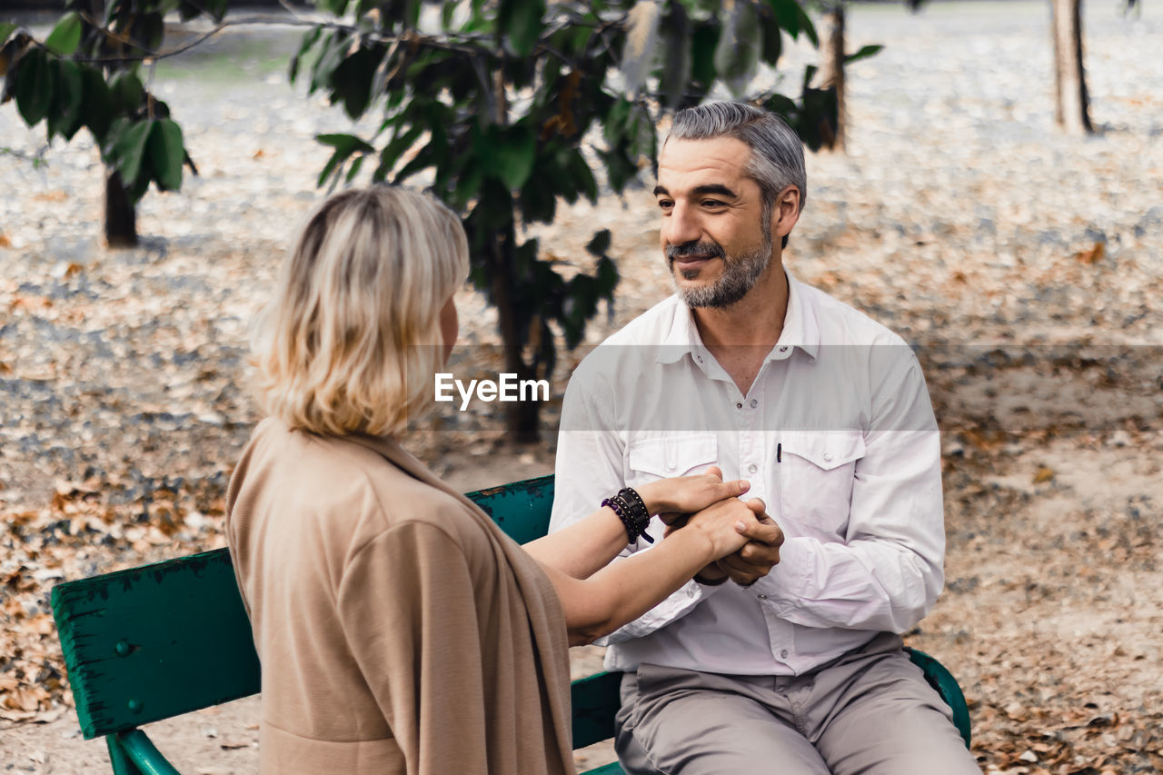 Couple holding hands while sitting at bench