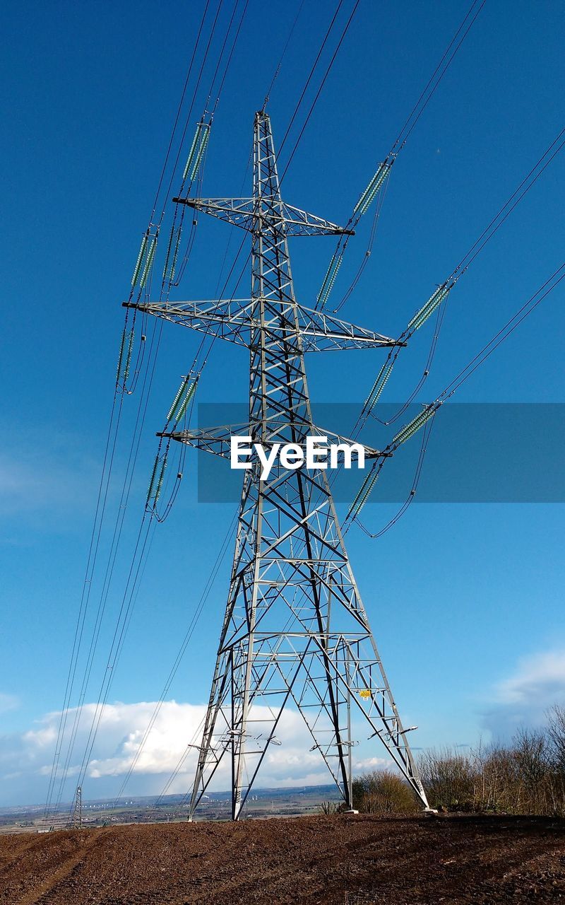 Low angle view of electricity pylon against blue sky