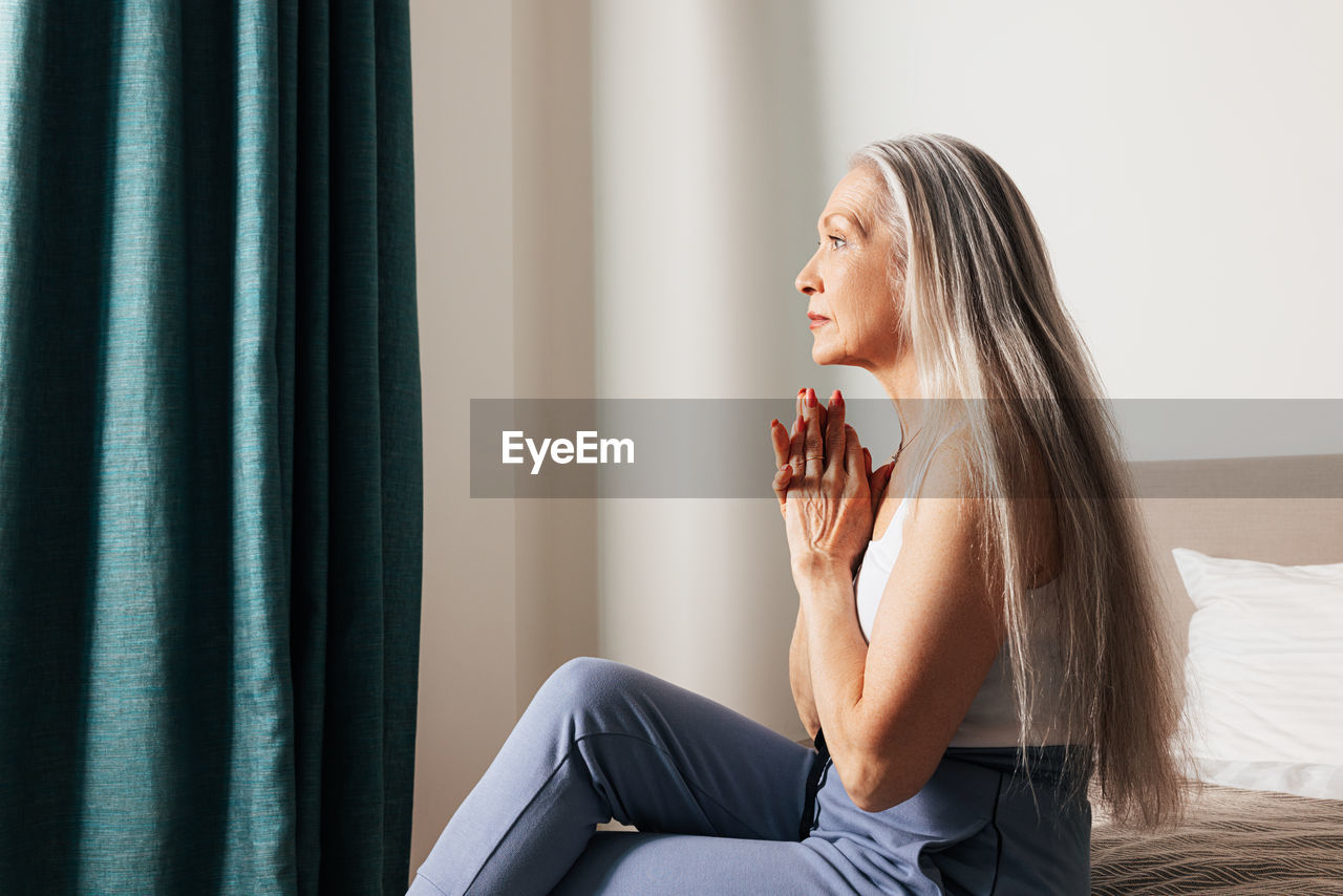 side view of young woman looking away while sitting on sofa at home