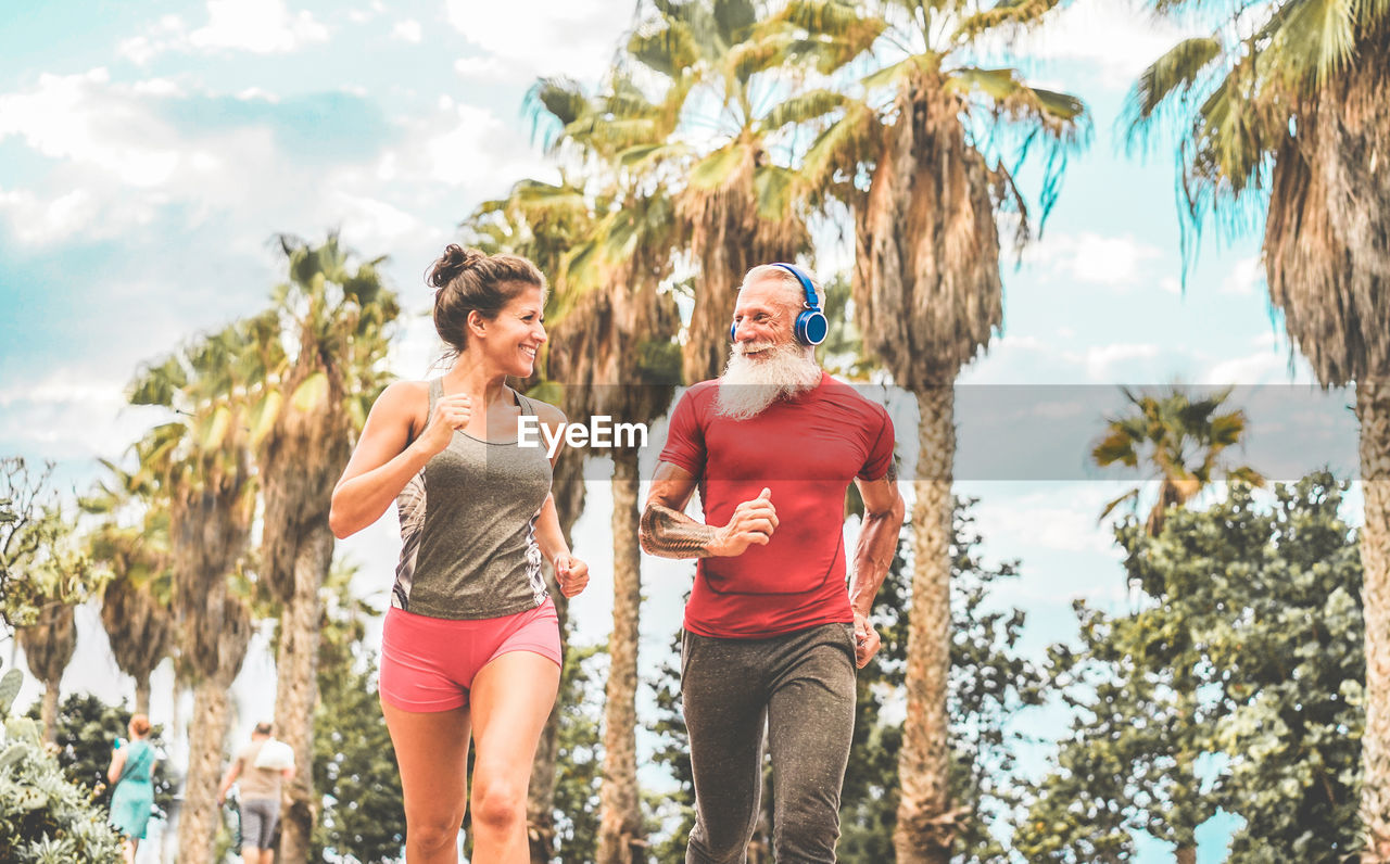 Smiling friends jogging against palm trees