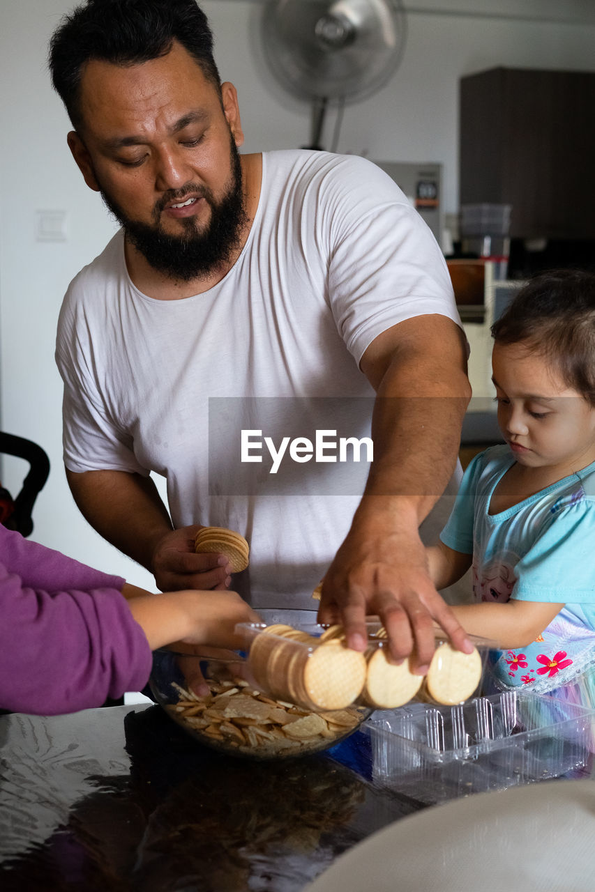 Father giving food to daughter at home