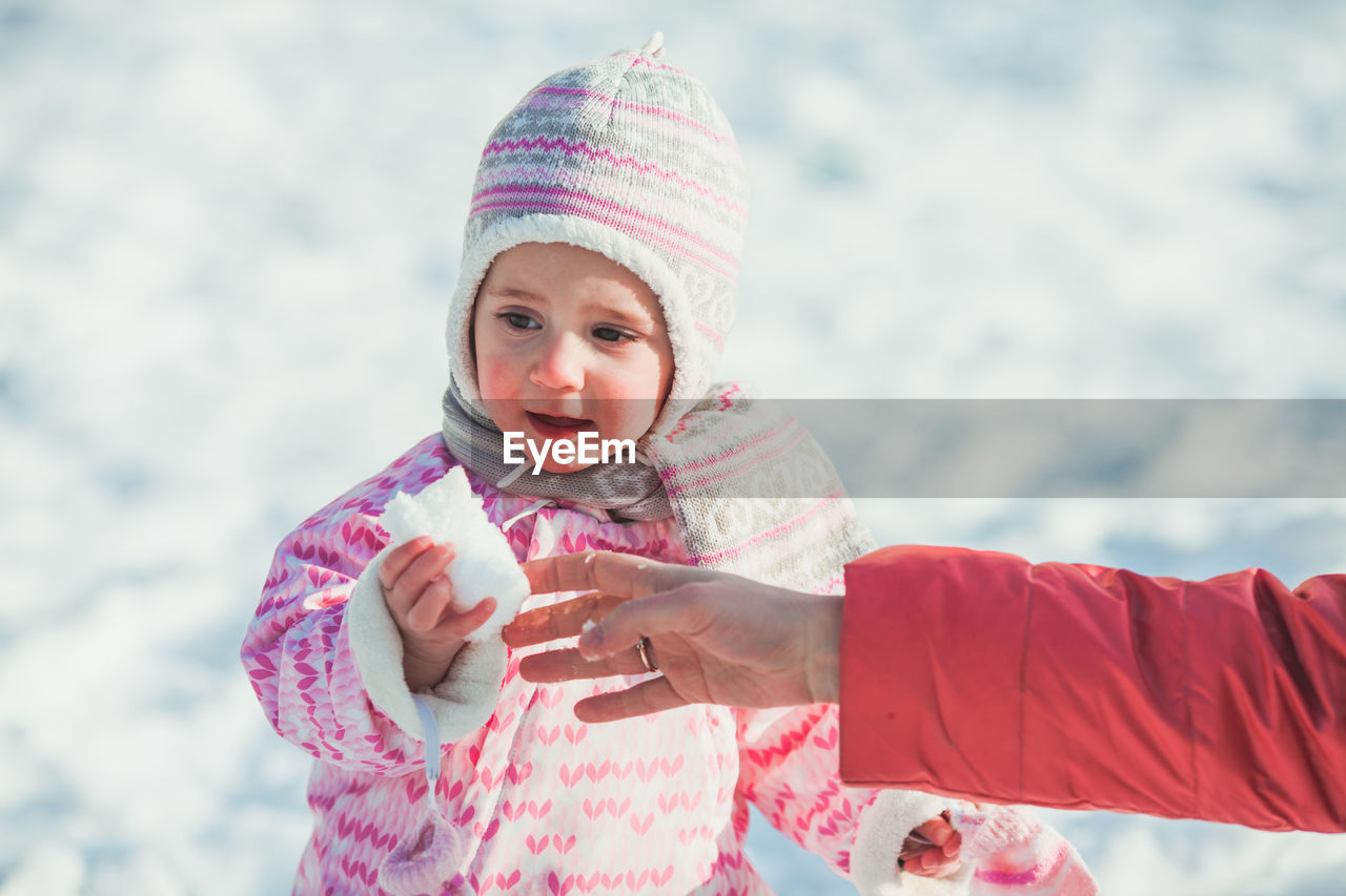 Portrait of cute girl holding hat during winter