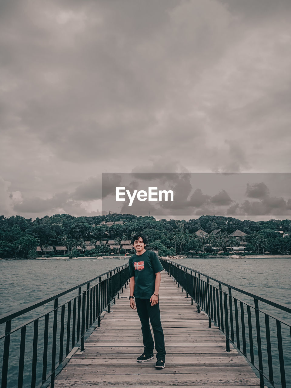 MAN STANDING ON RAILING AGAINST BRIDGE