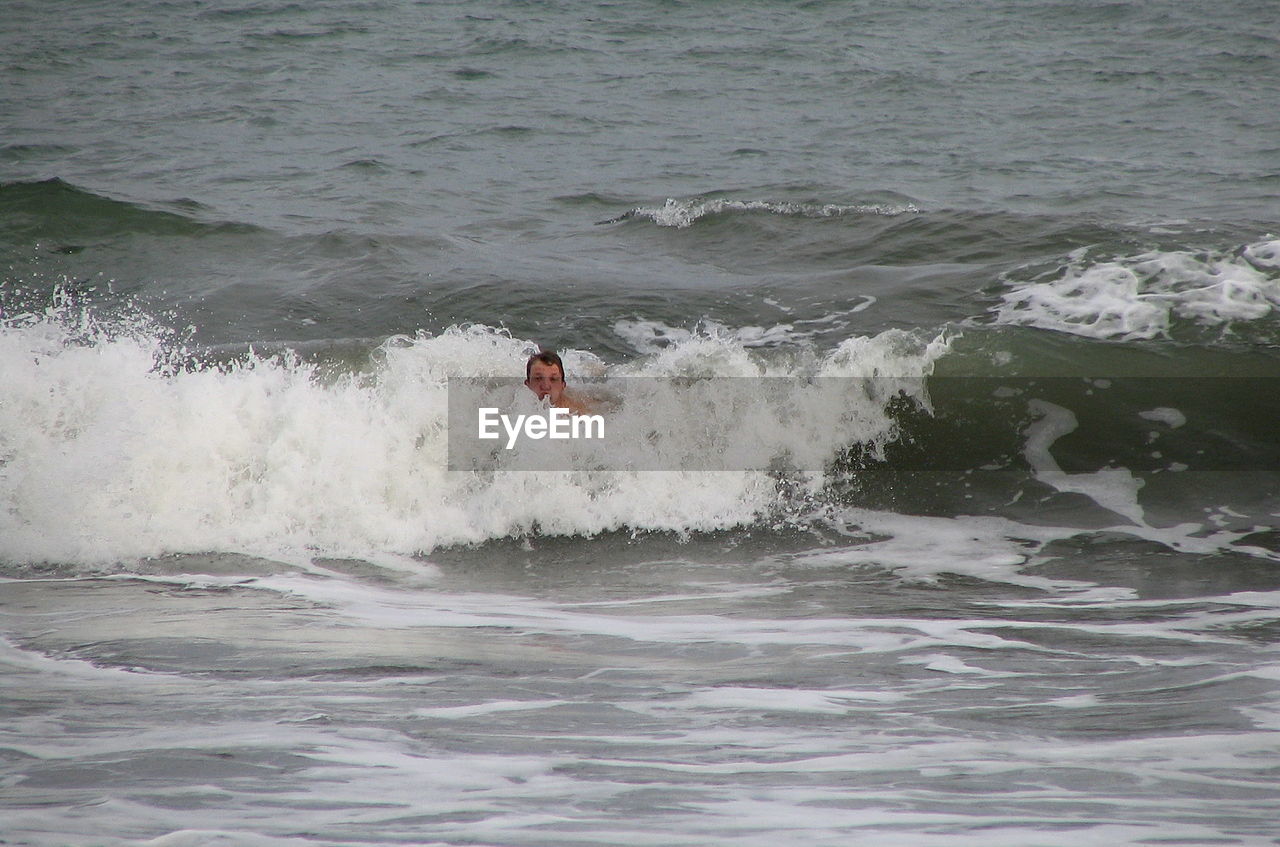 MAN SURFING ON SEA WAVES