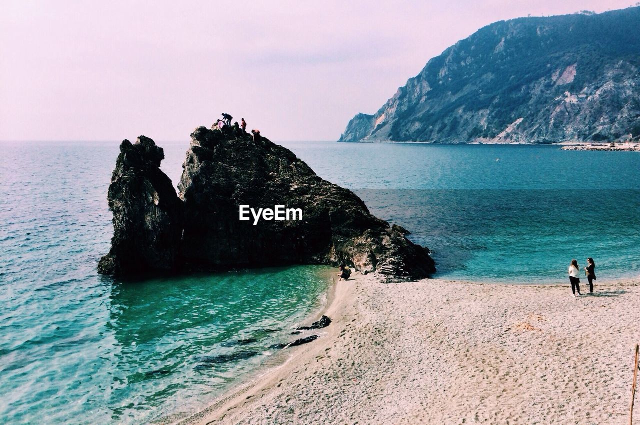 People on top of rock at beach