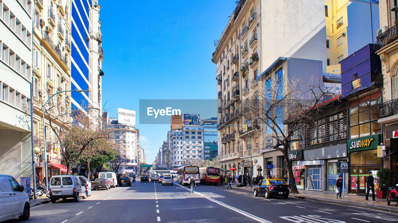 CITY STREET AMIDST BUILDINGS AGAINST SKY