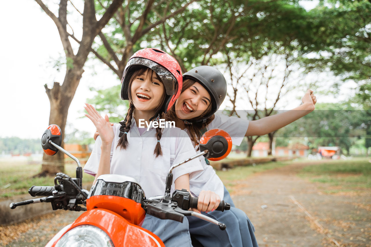 portrait of smiling young woman riding bicycle on field