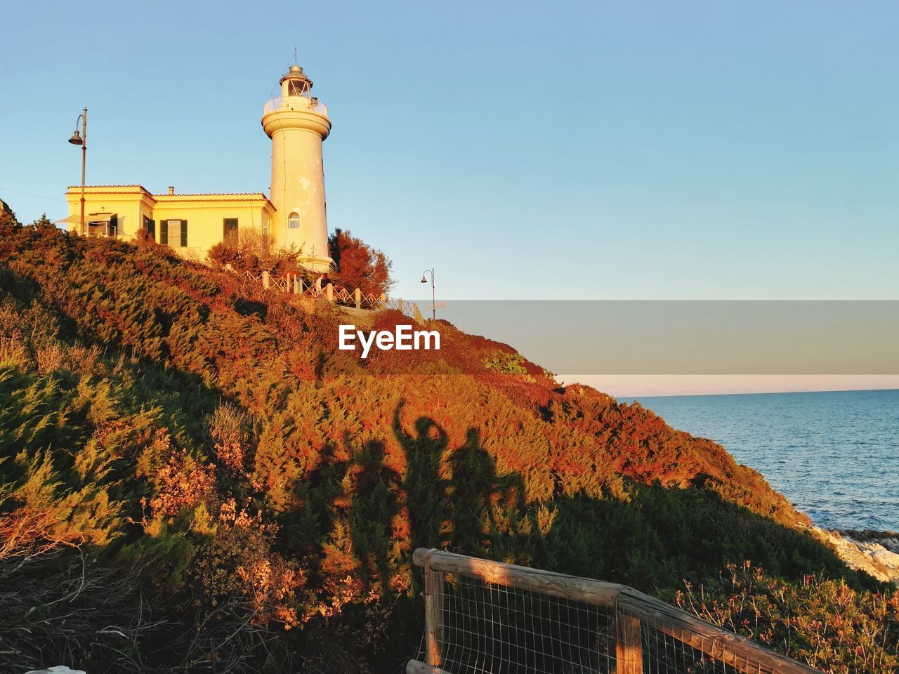 SCENIC VIEW OF LIGHTHOUSE BY SEA AGAINST CLEAR SKY